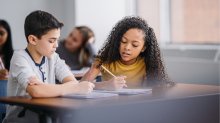 A photo of two elementary students talking through a math problem together
