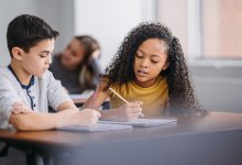 A photo of two elementary students talking through a math problem together