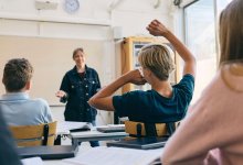 Teacher talking while student raises a hand