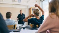 Teacher talking while student raises a hand