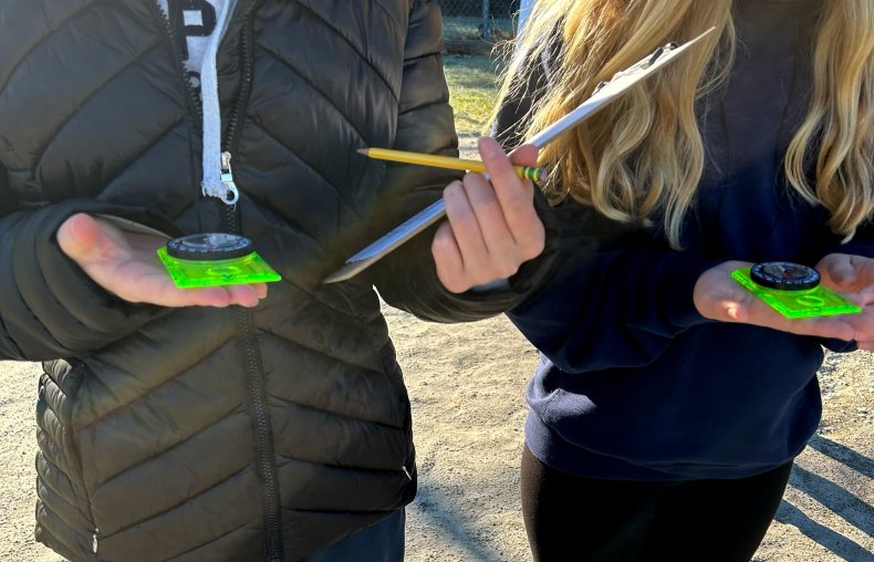 A photo of two students holding a clipboard and compasses